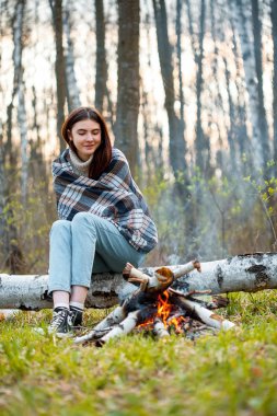 Genç bir kadın akşam ateşin yanında oturuyor.