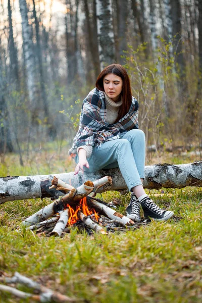 A young woman is heated near the fire at evening