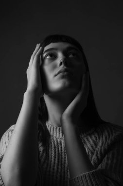 Yüzünde elleri olan genç bir kadın. Siyah ve beyaz