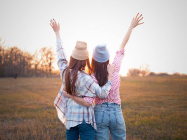 En iyi iki arkadaş gün batımını seyrediyor ve ellerini kaldırıyor. Geri