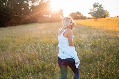 Mutlu genç kadın gün batımında dışarıda yürüyor..