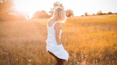 Gün batımında dışarıda yürüyen genç bir kadın. Geri