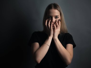 Gri arka planda korkmuş genç bir kadının portresi