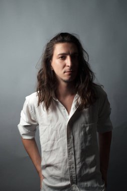 Gri arka planda genç bir adam. Stüdyo resmi