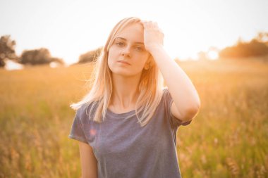 Gün batımında dışarıda poz veren genç bir kadın..