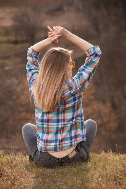 Sonbaharda uçurumda oturan genç bir kadın. Geri