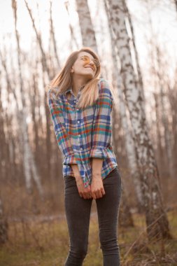 Genç bir kadın sonbaharda huş ağacında eğleniyor.