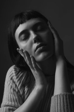 Yüzünde elleri olan genç bir kadın. Siyah ve beyaz. Kapat.