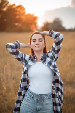 Gün batımında sahada poz veren çekici genç bir kadın.