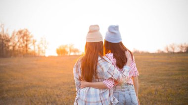 En iyi iki arkadaş gün batımını seyrediyor ve ellerini kaldırıyor. Geri