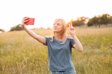Gün batımında selfie çeken genç bir kadın.