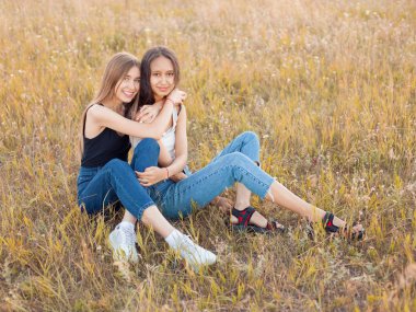Çimlerin üzerinde oturan iki güzel kız. En iyi arkadaşlar