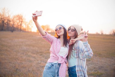 İki genç kadın gün batımında açık havada srlfie atıyorlar. En iyi arkadaşlar