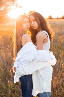 Gün batımında tarlada poz veren iki genç kız