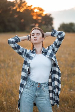 Gün batımında dışarıda poz veren güzel bir kız. Gözler kapalı