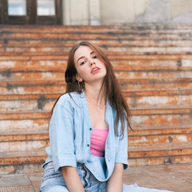 Yaşlı paslı merdivenlerde poz veren genç bir kadın.