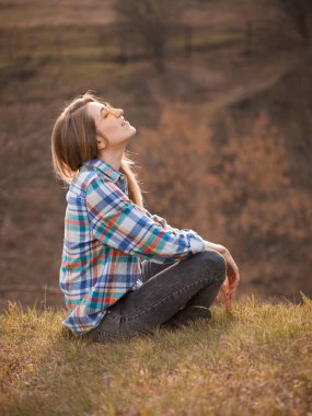 Sonbaharda uçurumda oturan çekici genç bir kadın. Profil