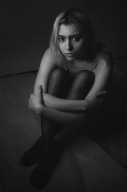 Yerde oturan üzgün genç kadın. Siyah beyaz