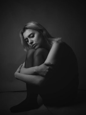 Yerde oturan üzgün genç kadın. Siyah beyaz