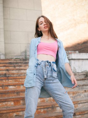 Genç, güzel bir kadın eski paslı merdivenlerde poz veriyor.