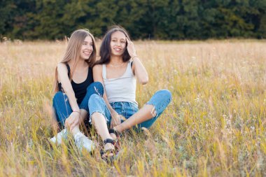 Çimenlerde oturup eğlenen iki güzel genç kadın. En iyi arkadaşlar