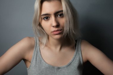 Gri arka planda mutsuz bir kızın portresi. Stüdyo