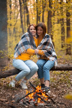 Şenlik ateşinin yanındaki ormanda oturan iki kız. En iyi arkadaşlar