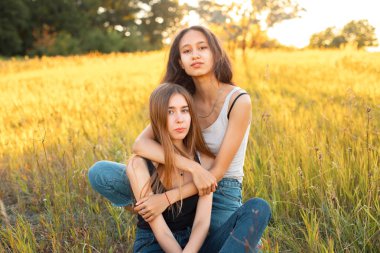 İki çekici kız güneşin altında çimlerin üzerinde oturuyor.