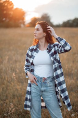 Gün batımında dışarıda poz veren genç bir kadın. Profil