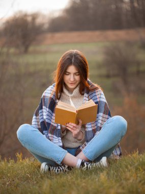 güzel genç kadın açık havada bir kitap okuma.