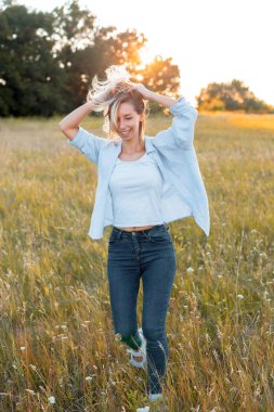 Gün batımında sahada yürüyen genç bir kadın..