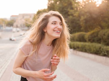 Genç bir kadın şehirde gün ışığında eğleniyor ve gülüyor.