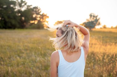 Gün batımında sahada genç bir kadın. Geri.