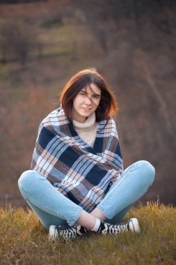 Genç ve güzel bir kadın çimlerin üzerinde oturuyor.