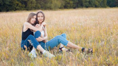 Çimlerin üzerinde oturan iki güzel genç kadın. En iyi arkadaşlar