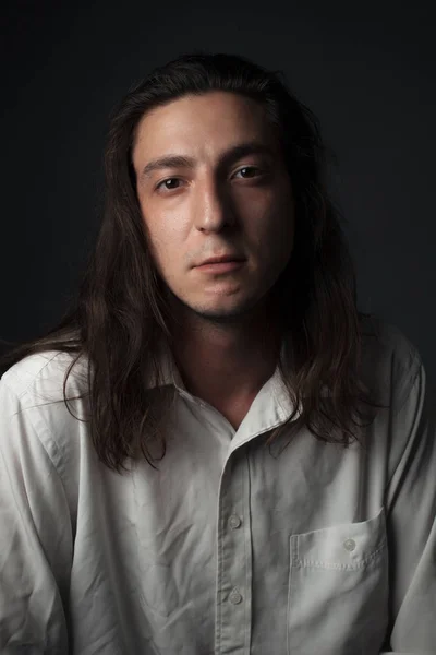 Portrait of a young man with long hair. Studio