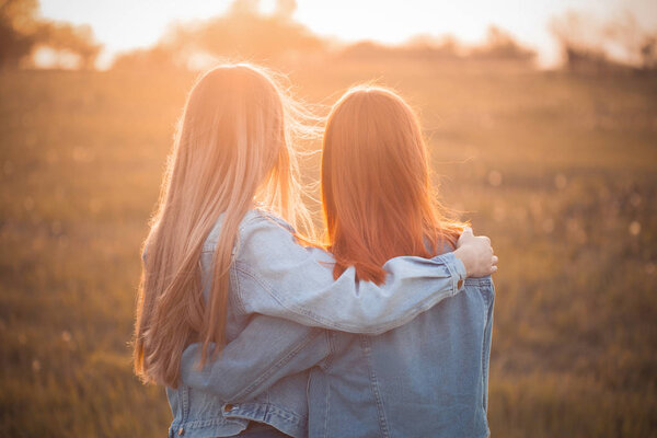 Two young women looking on the sunset. Best friends