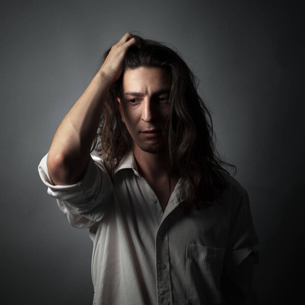 Worried young man on gray background. Studio portrait