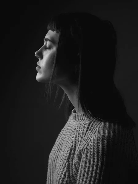 Portrait of young woman in profile with closed eyes. Low key. Black and white.