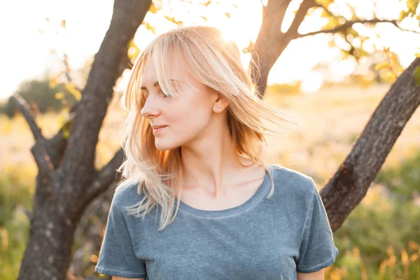 Młoda Kobieta Blond Włosami Stojąca Przy Drzewie Pod Słońcem — Zdjęcie stockowe