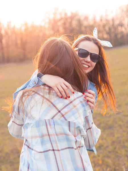 Two best friends hugging outdoors at sunset