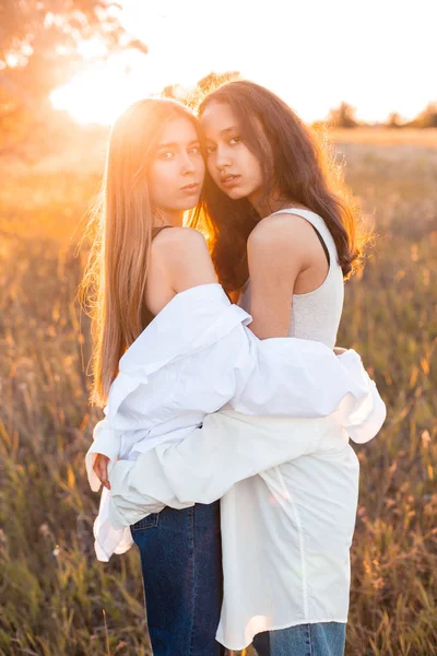 Gün batımında tarlada poz veren iki genç kız