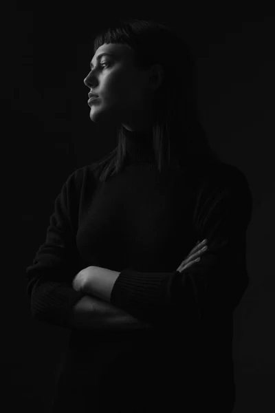 Portrait of young woman in profile. Low key.  Black and white