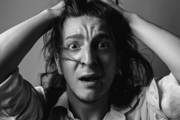 Young man with long hair in fear. Black and white.