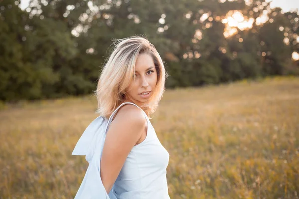 Gün batımında dışarıda yürüyen genç bir kadın. Dön