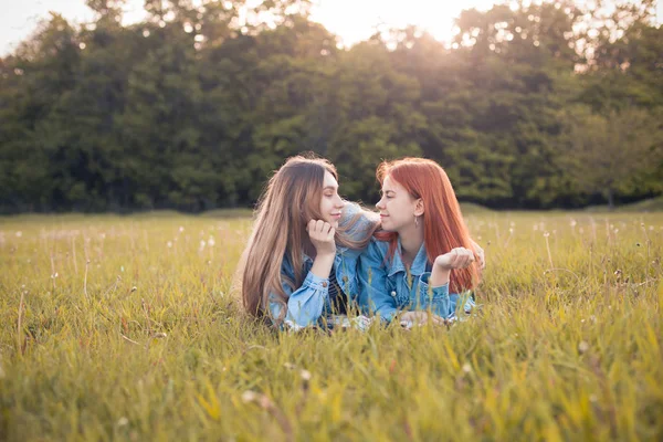 二人の若い女性が草の上に横になり お互いを見ています 親友だ — ストック写真