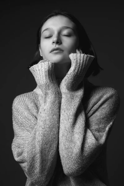 Portrait of a girl in sweater. Black and white. Eyes closed.