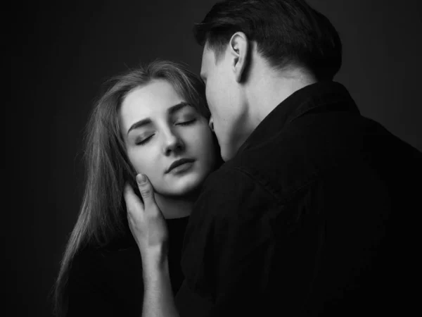 Young man and woman kissing in studio. Black and white