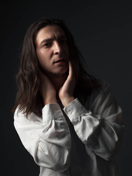 Portrait of a worried young man with long hair. Low key