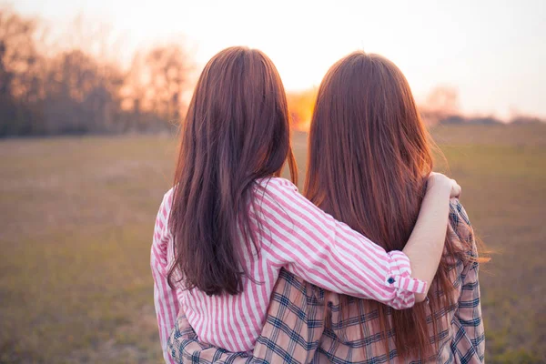 两个年轻女子站在室外 看着日落 回来了 — 图库照片